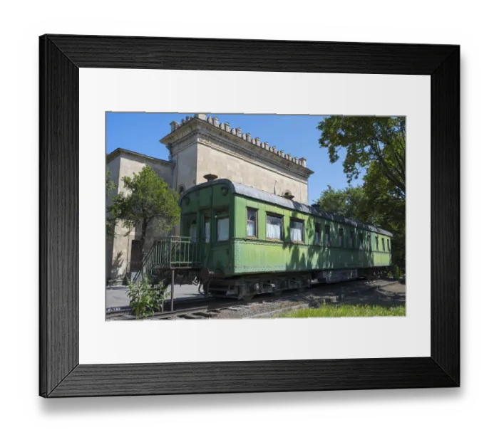 Framed Print : Old green railroad car in front of historic building and trees Framed Print : Old green railroad car in front of historic building and trees