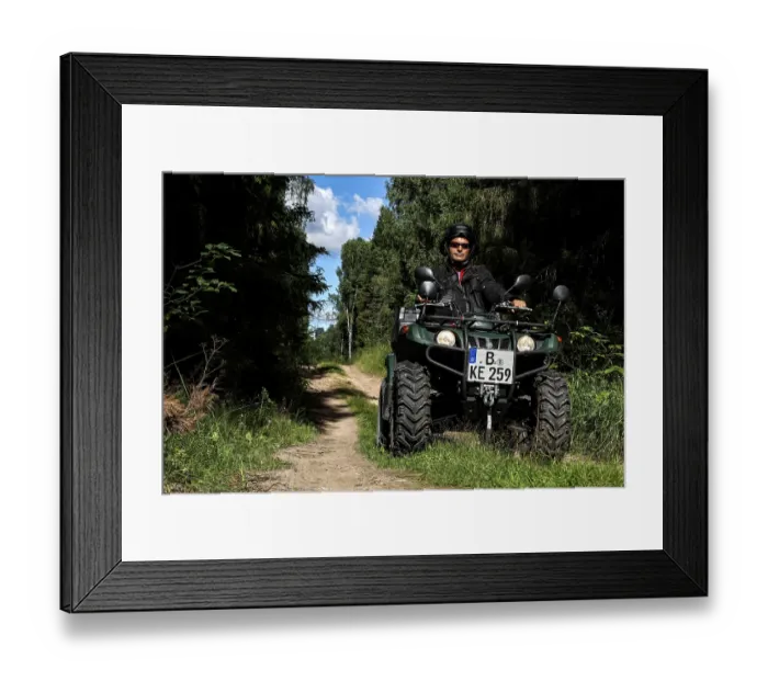 Framed Print : Man rides ATV on a forest trail surrounded by tall vegetation