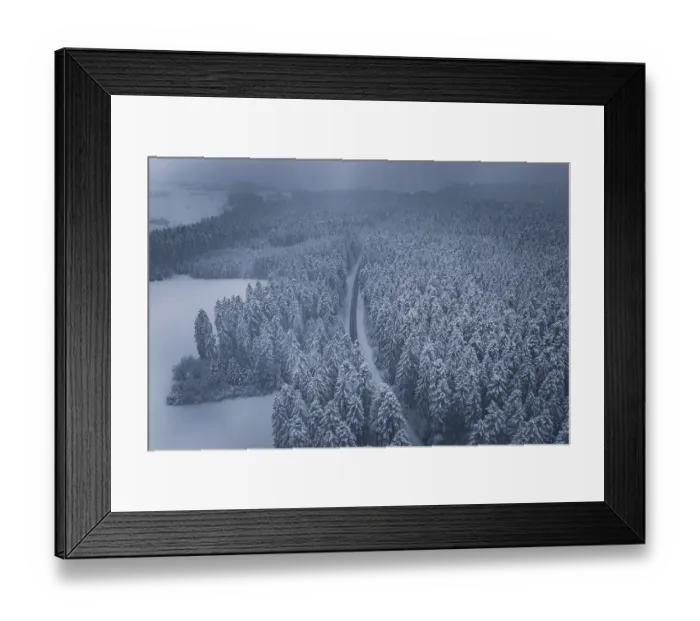 Framed Print : Snowy road and forests under a grey sky
