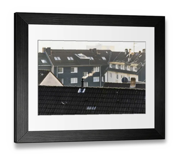 Framed Print : Smoke plume from a chimney over densely built residential area in the evening light