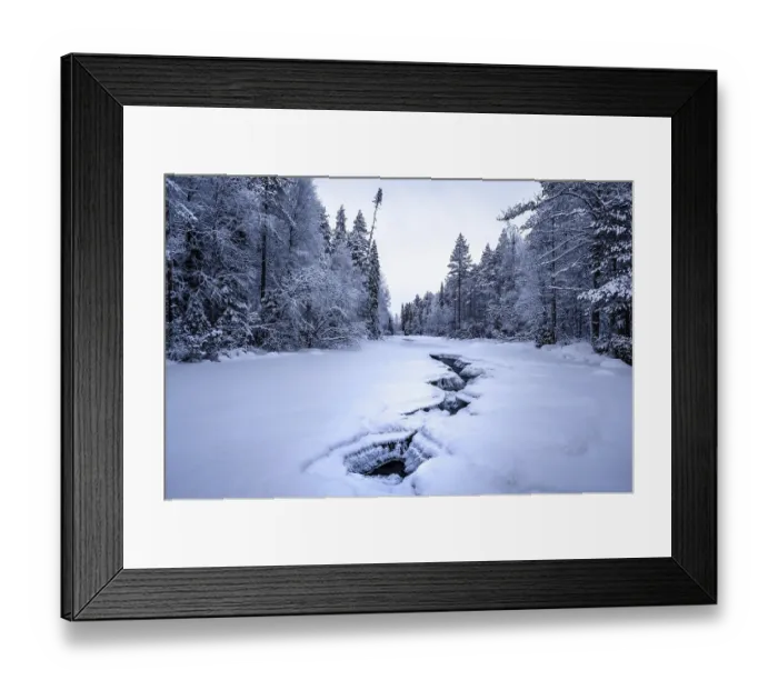Framed Print : Frozen river with cracks between snowy trees in a quiet winter forest