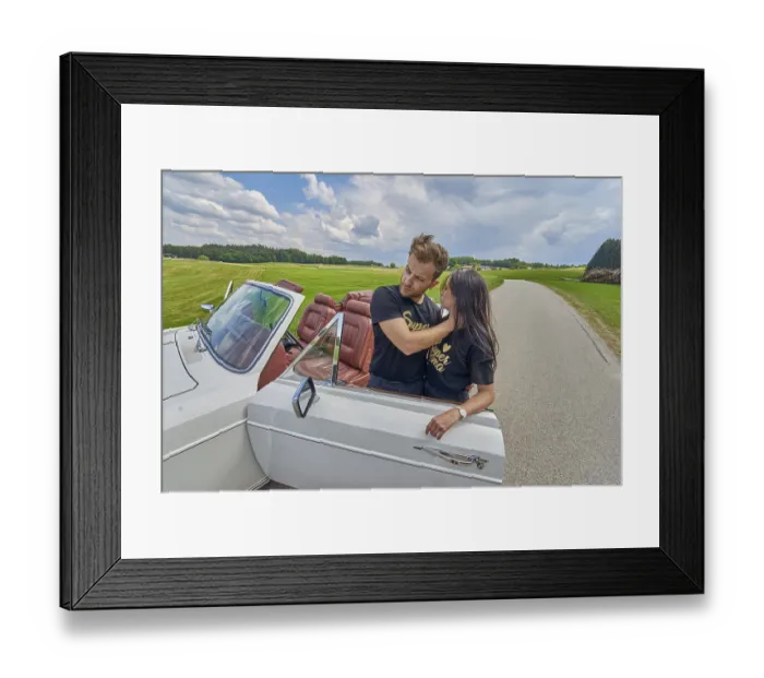 Framed Print : Couple embracing by a convertible car on a tranquil country road Framed Print : Couple embracing by a convertible car on a tranquil country road