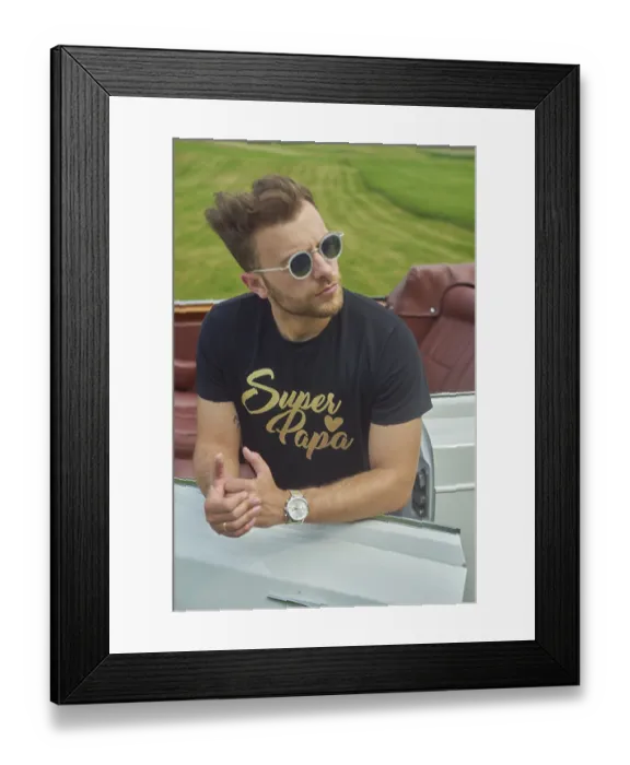 Framed Print : Man in sunglasses leaning casually on a convertible set against a scenic green field Framed Print : Man in sunglasses leaning casually on a convertible set against a scenic green field
