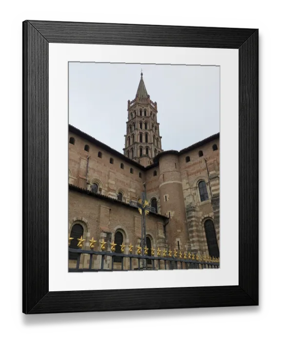 Framed Print : Imposing historic structure with a tall Romanesque tower and brick facade under a cloudy sky