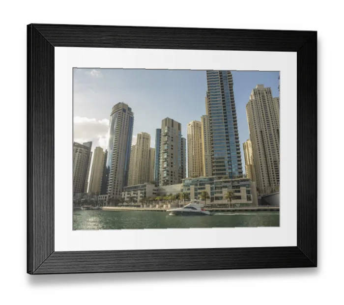 Framed Print : Modern skyscrapers and a boat on a city waterway under the sun
