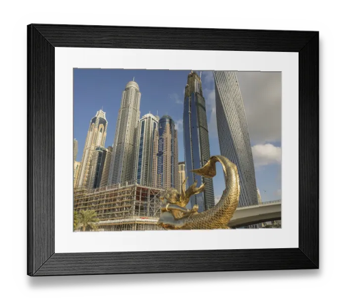 Framed Print : Golden sculpture in front of modern skyscrapers under blue sky