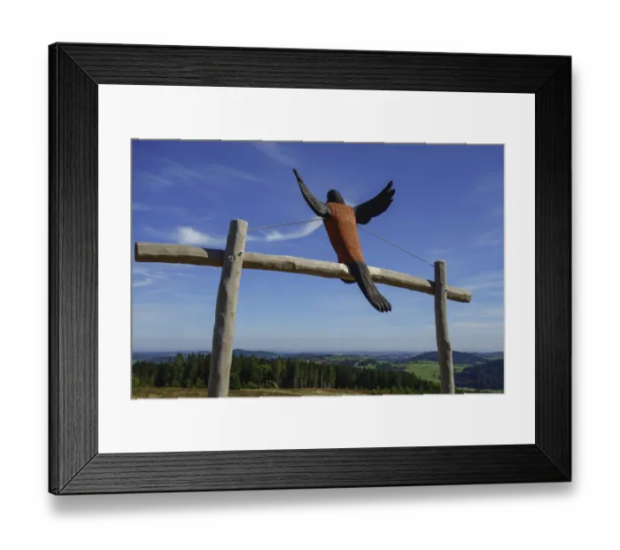 Framed Print : A wooden sculpture of a bird spreading its wings in front of a wide landscape view