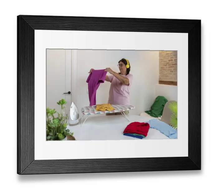 Framed Print : Woman folding colorful clean clothes on an ironing board