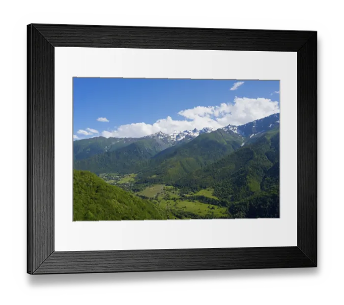 Framed Print : Green valley with densely wooded slopes and distant mountains under blue sky with clouds Framed Print : Green valley with densely wooded slopes and distant mountains under blue sky with clouds