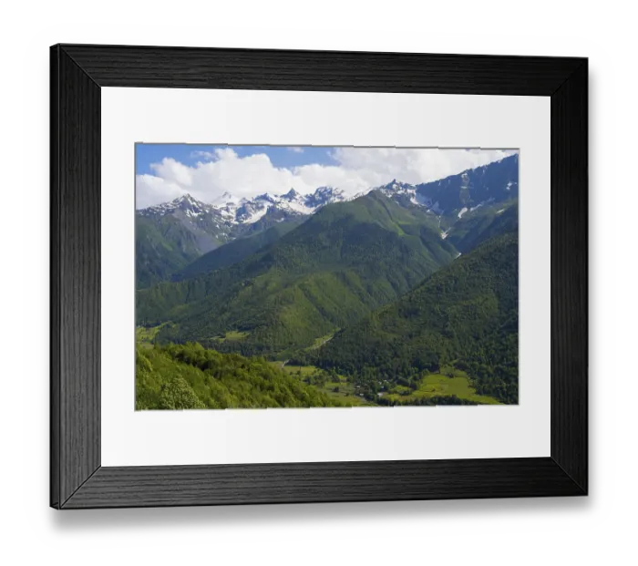 Framed Print : Wide green valley with snow-covered mountains in the background under clear sky Framed Print : Wide green valley with snow-covered mountains in the background under clear sky
