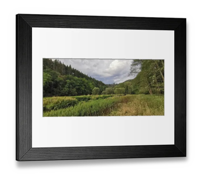 Framed Print : Meadows and forests stretch under a sky full of clouds