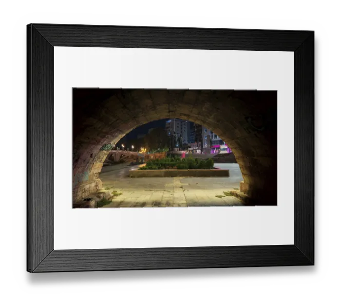 Framed Print : View through a stone archway of an illuminated square with monuments at night