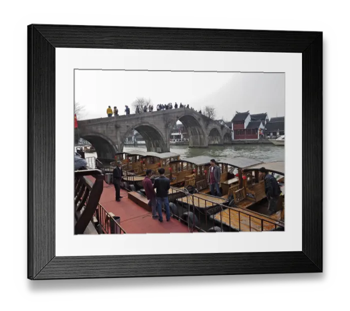 Framed Print : People on a stone bridge admire the wooden boats on the river in a historic city setting