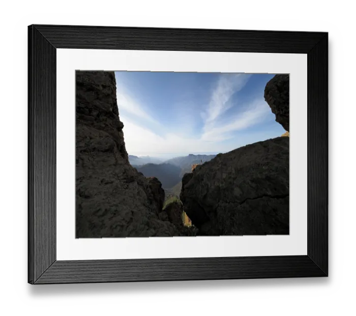 Framed Print : View through rocks of a vast mountain landscape under clear sky