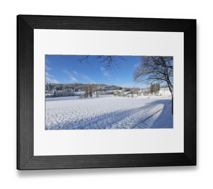 Framed Print : Winter landscape with snow-covered fields and trees under a blue sky