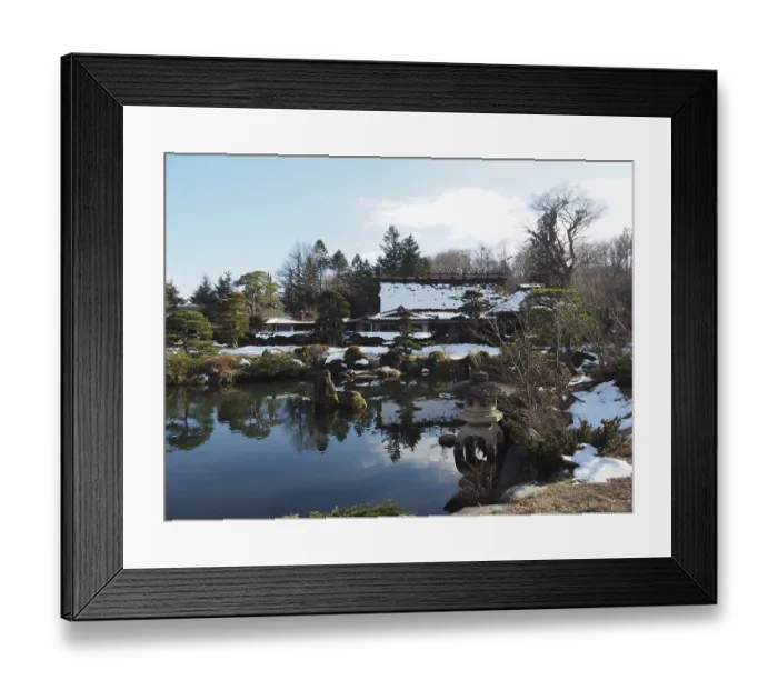 Framed Print : Snowy Japanese garden with small ponds and traditional buildings in the background