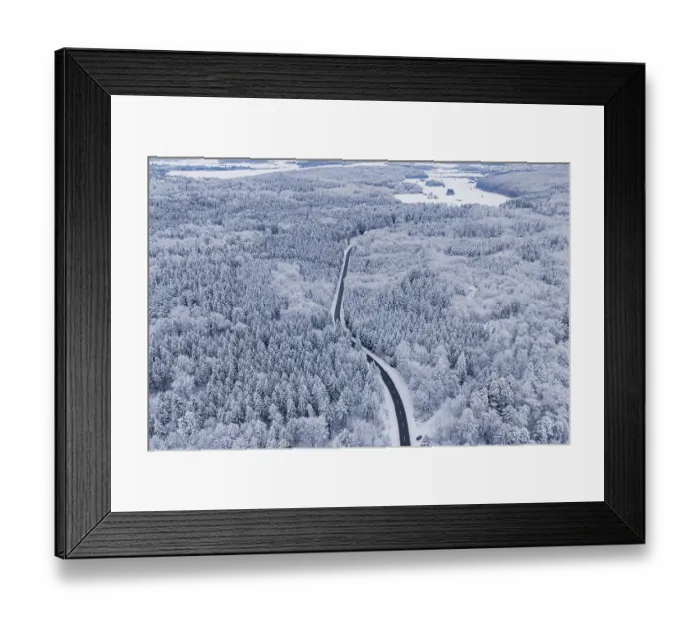 Framed Print : Snow-covered road leads through a vast winter forest