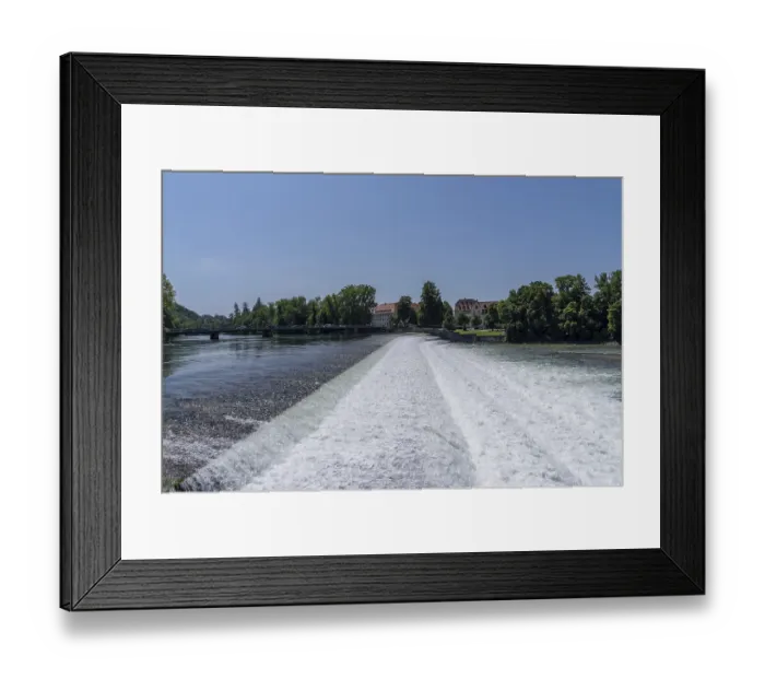 Framed Print : River Lech flowing over a weir with old town architecture under a clear blue sky