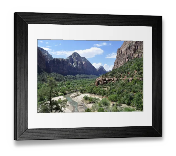 Framed Print : River flows through a lush valley surrounded by imposing mountains and green vegetation Framed Print : River flows through a lush valley surrounded by imposing mountains and green vegetation