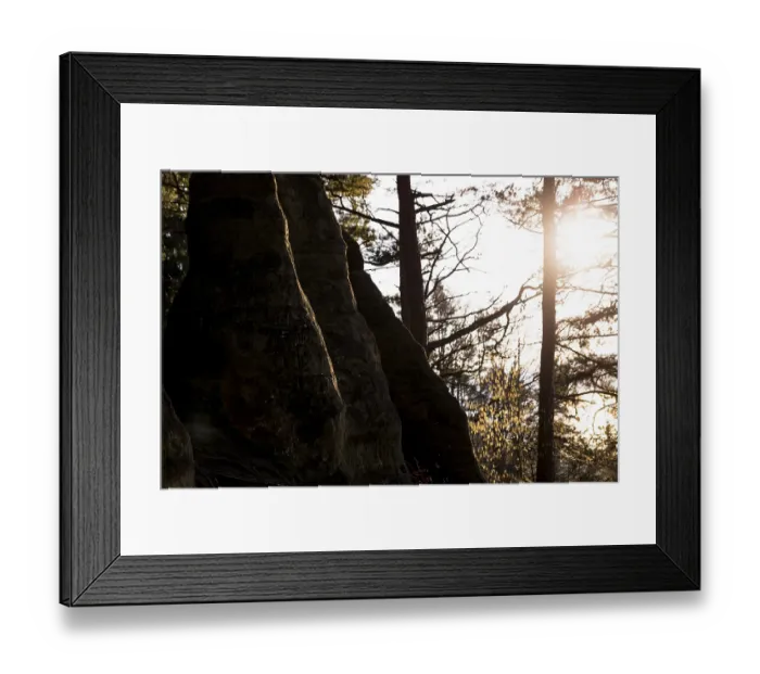 Framed Print : Rocks in shade, sun rays through trees in the background