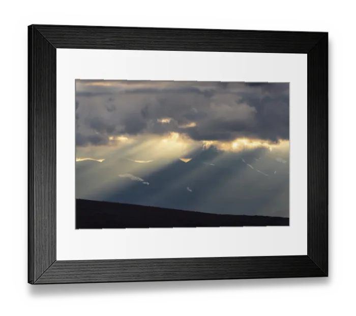 Framed Print : Sun rays fall through clouds in mountain landscape