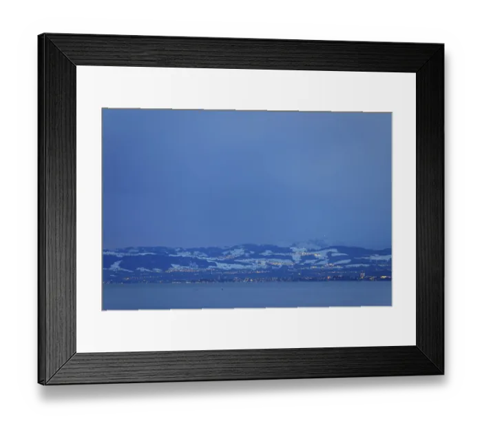Framed Print : Snowy mountain landscape at dusk with view of lake and city lights
