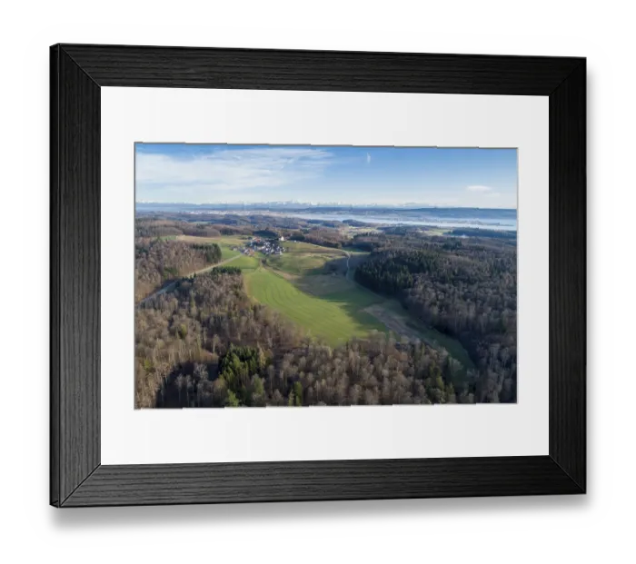 Framed Print : Aerial view of fields and forests with a village in the distance and mountains in the background