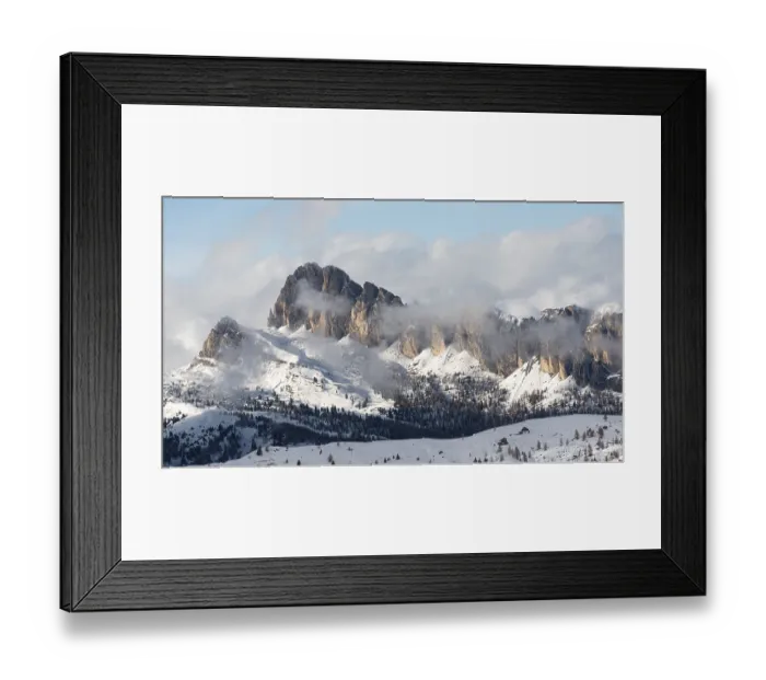 Framed Print : Snow-covered mountain peaks with clouds rolling over in a serene winter landscape