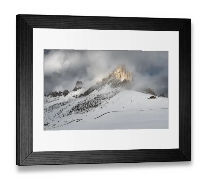 Framed Print : Snowy mountain landscape with dramatic clouds and sunlight illuminating rugged peaks
