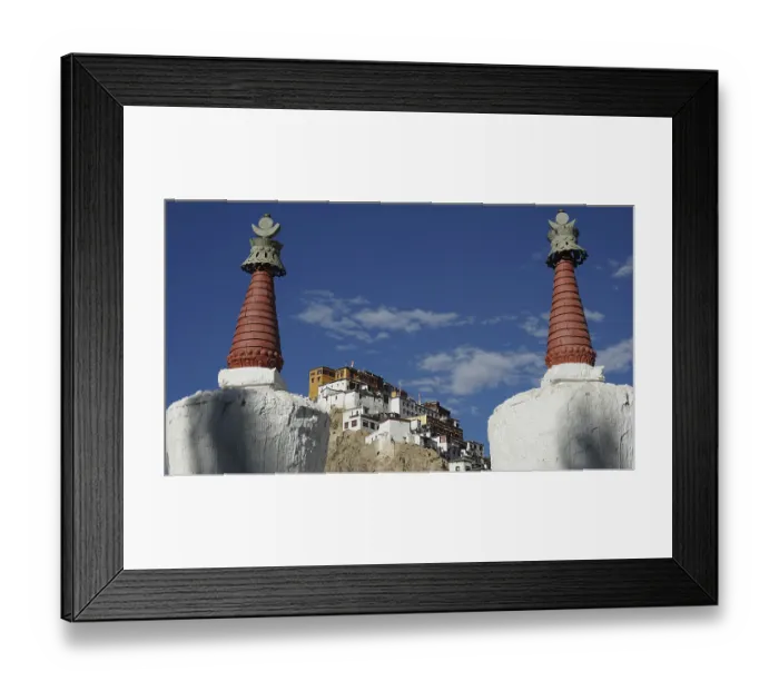 Framed Print : View through two stupas towards Thiksey monastery on a hill under blue sky