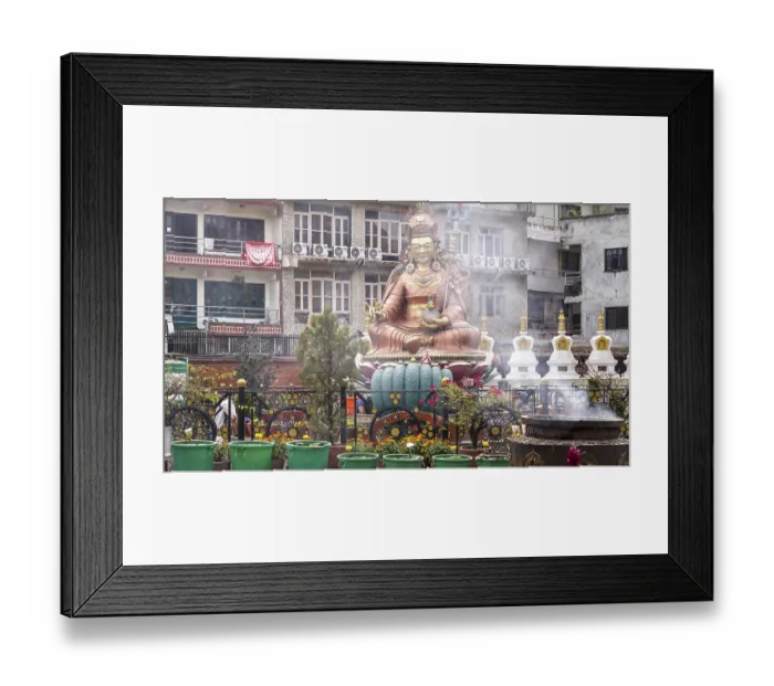 Framed Print : Buddhist statue in an urban setting with religious symbols and plants