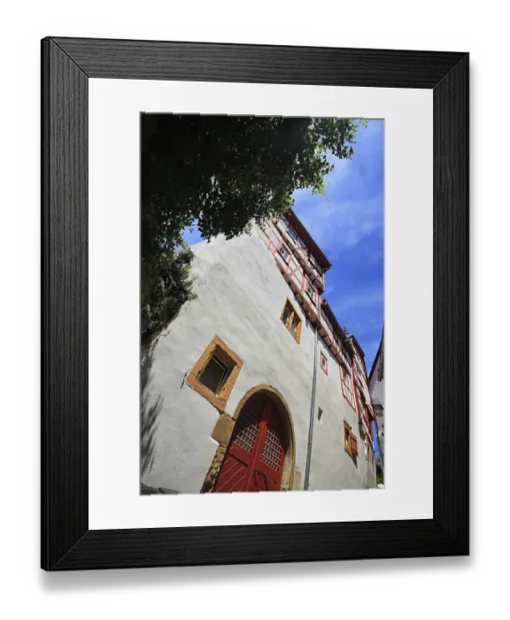Framed Print : Large half-timbered house with red doors and windows under a blue sky in Bad Wimpfen