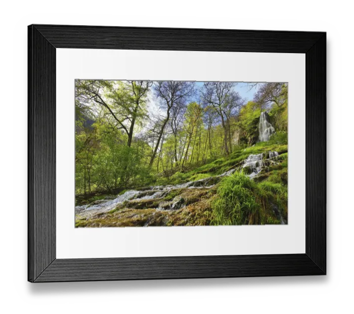 Framed Print : Urach waterfall with flowing water over moss-covered rocks in a wooded area