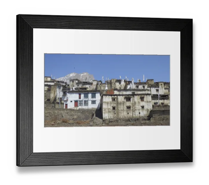 Framed Print : Traditional white-painted buildings in a mountain village with prayer flags against a clear sky