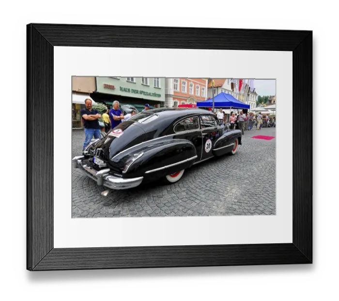Framed Print : A black luxury classic car in front of a building surrounded by people