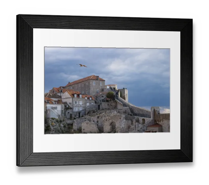 Framed Print : Walkway up to the sunshined stone fortress of Dubrovnik with dramatic cloudscape and gull flying over it Framed Print : Walkway up to the sunshined stone fortress of Dubrovnik with dramatic cloudscape and gull flying over it