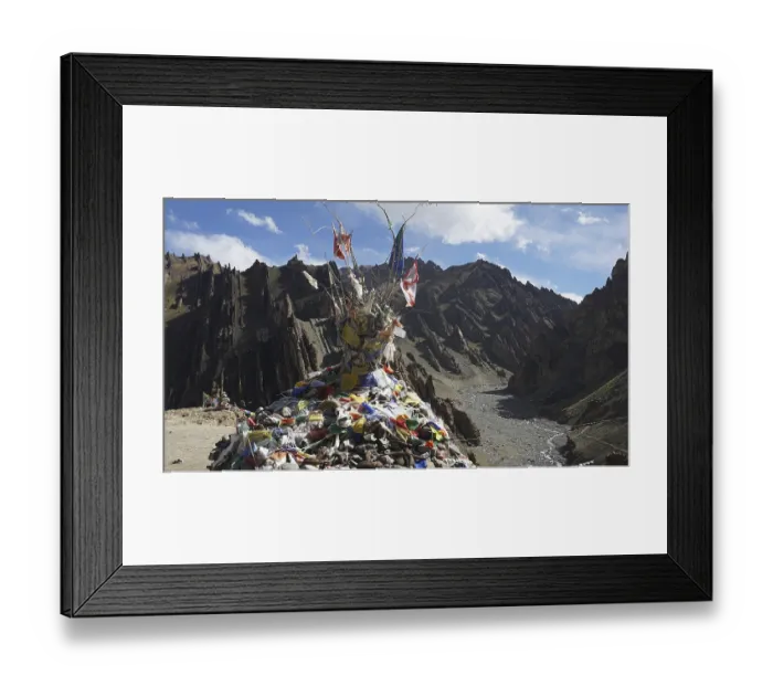 Framed Print : Traditional prayer flags on a stone hill in a wide mountain valley with a dry riverbed