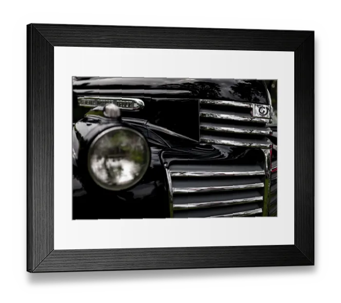 Framed Print : Front view of a vintage truck featuring a chrome grille and round headlight on a black finish in St