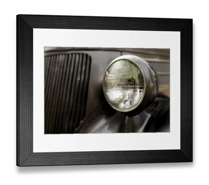 Framed Print : Detail of a classic car's headlight with chrome finish on a dark body in St