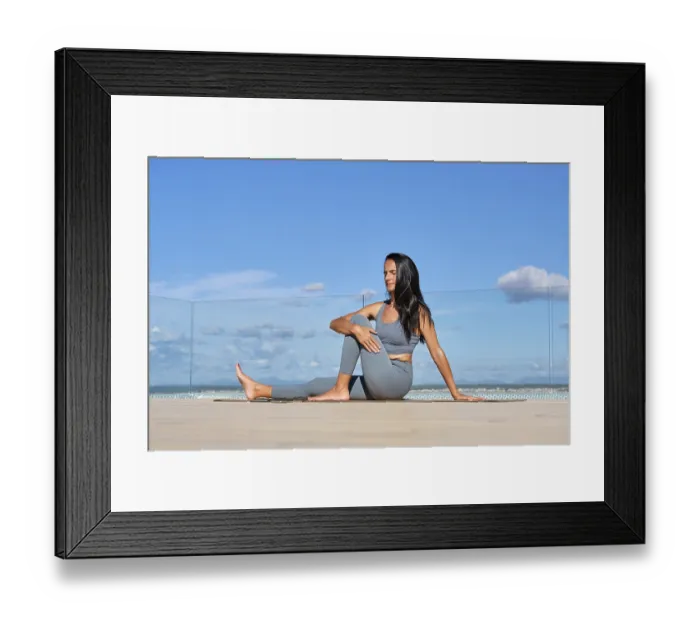 Framed Print : A woman meditatively practices yoga on a rooftop
