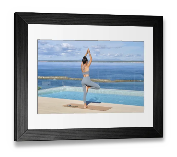 Framed Print : A woman stands in a yoga pose on a rooftop overlooking a serene ocean Framed Print : A woman stands in a yoga pose on a rooftop overlooking a serene ocean