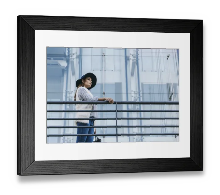 Framed Print : A fashionable woman wearing a stylish hat and chic attire stands confidently next to a modern glass building