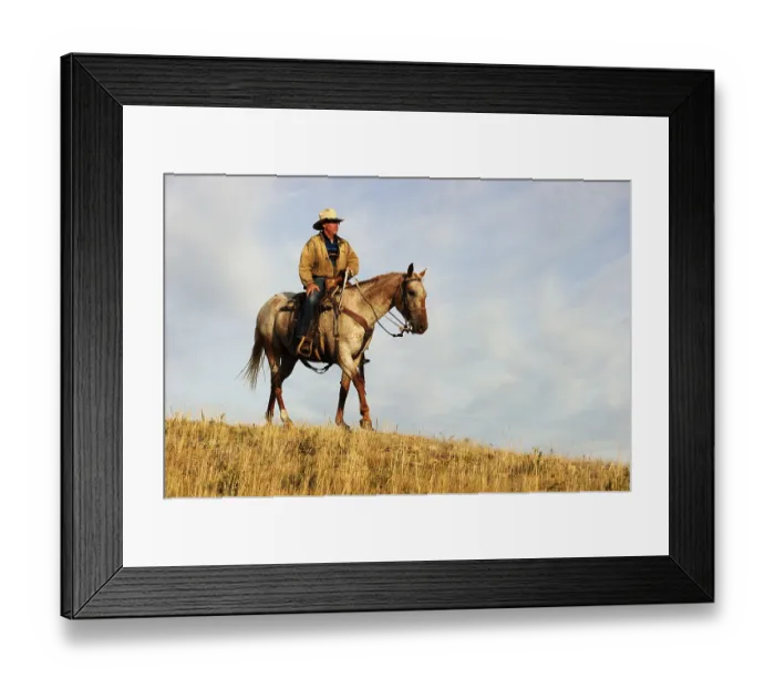 Framed Print : Cowboy riding a horse across the prairie