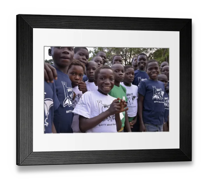 Framed Print : Children with flying fox T-shirts at an observation of palm fruit bats (Eidolon helvum) Kasanka National Park