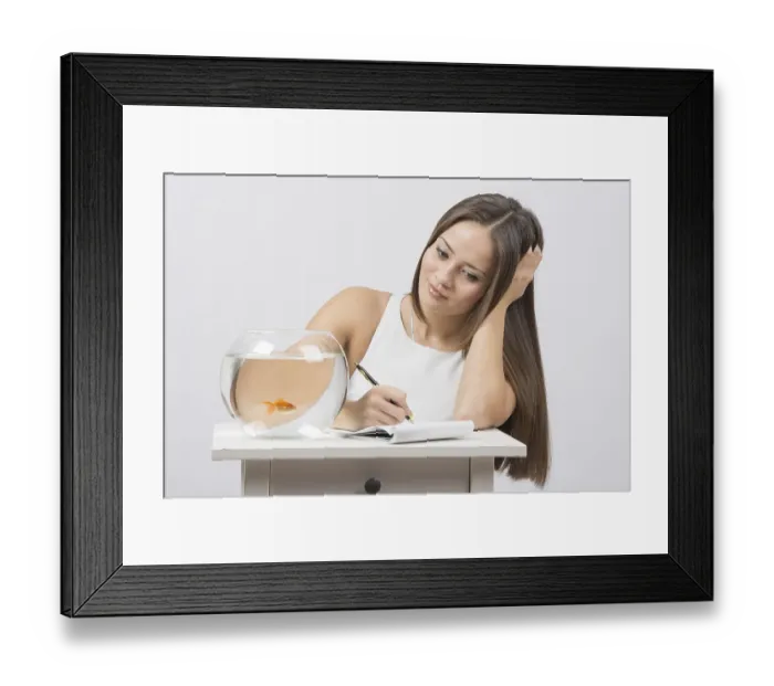 Framed Print : A young girl sits next to a round aquarium in which swimming goldfish