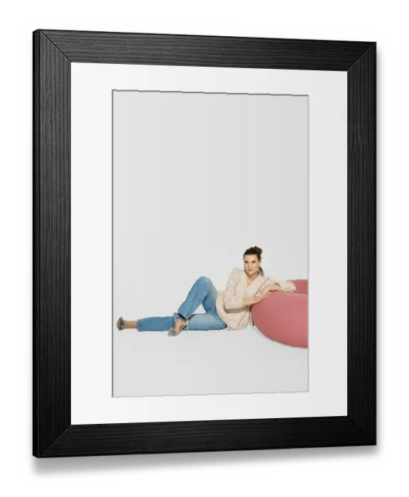 Framed Print : A woman sits on a floor near a pink piece of furniture in a bright studio