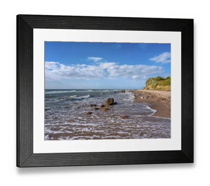 Framed Print : Unspoiled secluded stretch of coast with cliffs and boulders in the surf on the beach of the stormy Baltic Sea