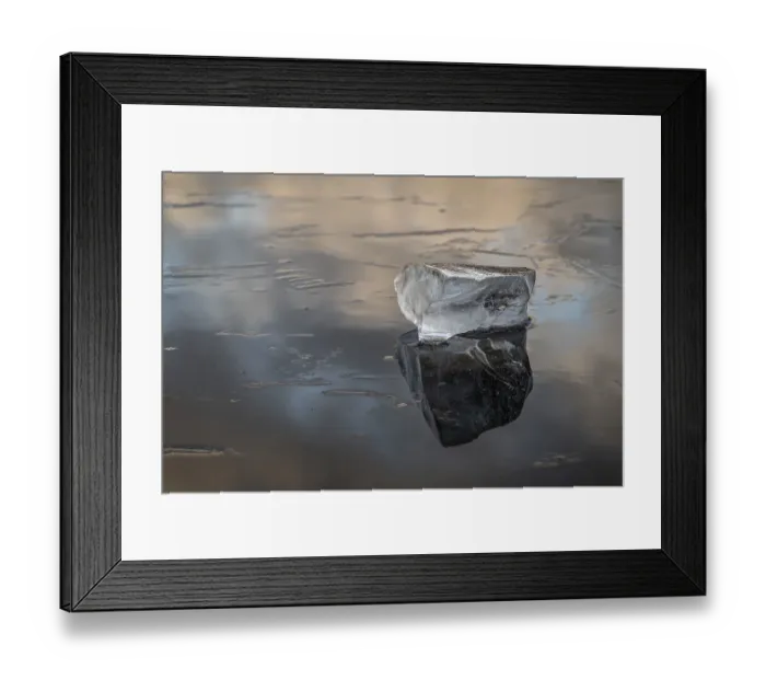 Framed Print : A piece of ice lies on the frozen surface of a lake in which clouds are reflected Framed Print : A piece of ice lies on the frozen surface of a lake in which clouds are reflected