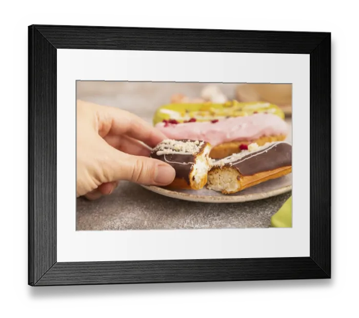 Framed Print : Glazed Eclairs on brown concrete background and green linen textile with hand