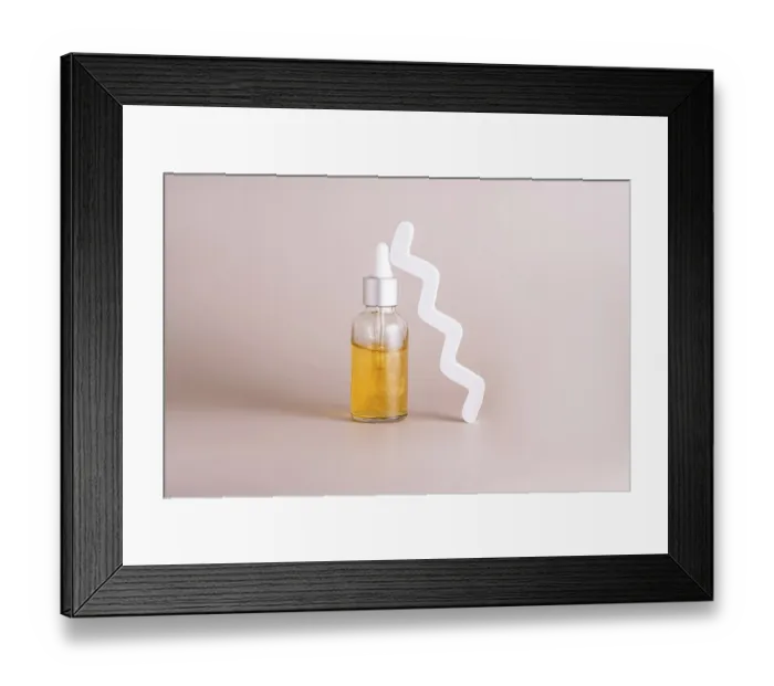 Framed Print : A minimalist shot of a skincare serum in a glass dropper bottle with golden liquid